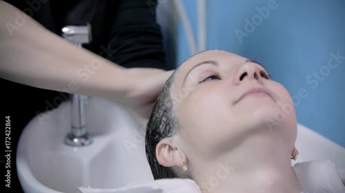 The hairdresser washes hair. Hairdresser makes hairstyle for young girl.