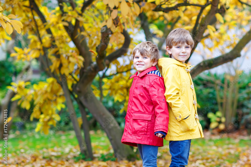 Two little best friends and kids boys autumn park in colorful cl Two little best friends and kids boys autumn park in colorful cl