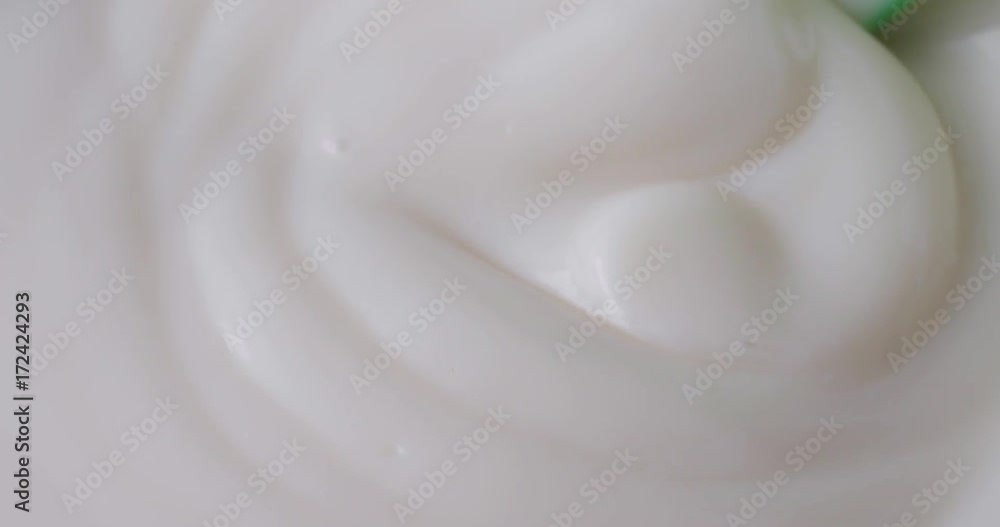 Close video of vanilla yogurt being stirred with a plastic green spoon. Close video of vanilla yogurt being stirred with a plastic green spoon.
