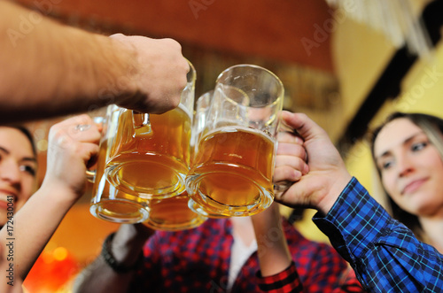 A company of friends drink beer and clink glasses at a pub