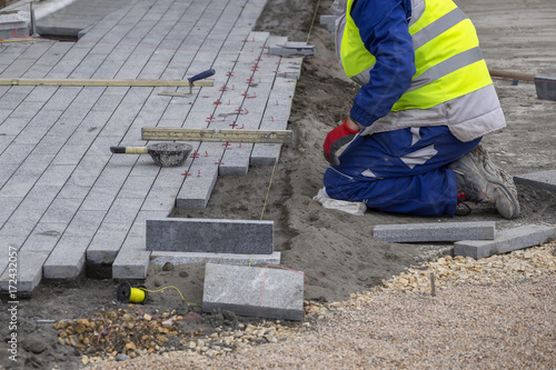 Worker installing paver sidewalk