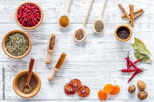 Variety of spices and dry herbs in bowls on wooden kitchen table background top view pattern