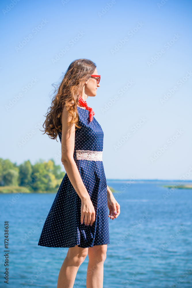 Portrait nice middle age thin woman in american pin up style. Lady in deep blue polka dot dress, red sunglasses and scarf Portrait nice middle age thin woman in american pin up style. Lady in deep blue polka dot dress, red sunglasses and scarf