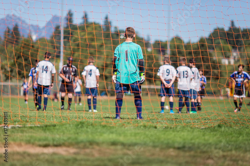 Young soccer goalkeeper and players getting ready for a penalty kick