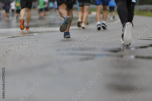 Marathon runners focus clear running shoes on the street with rain.