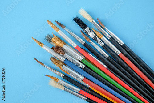 Row of artist paint brushes close up on blue background