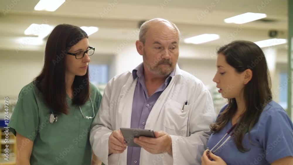 Nurses and doctor collaborate over a wireless tablet, slow slider shot. Nurses and doctor collaborate over a wireless tablet, slow slider shot.
