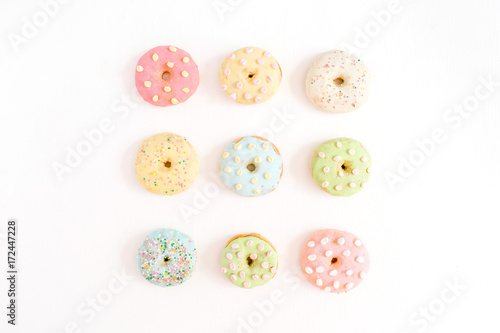 Colorful donuts on white background. Flat lay, top view minimal pattern.