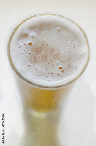 Glass of fresh cold beer with cap of foam