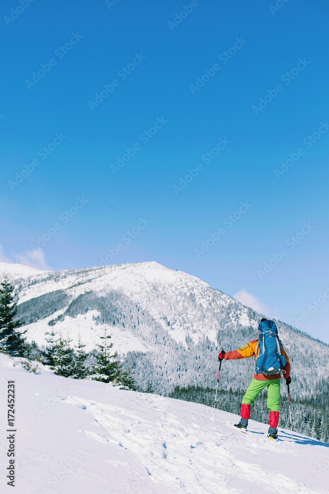 Winter hiking in the mountains on snowshoes with a backpack and tent.
