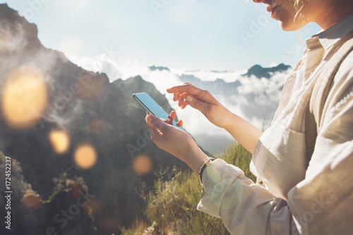 Photography Young traveling woman standing on top of  mountain at sunset and using mobile phone