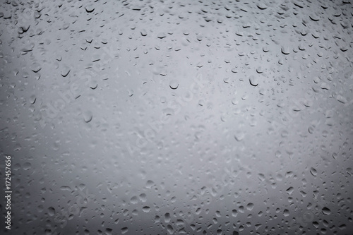 Drops of rain on a grey window glass. Close up detail of a wet surface water with copy space