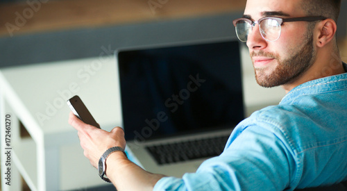 Young man using phone and works on the laptop