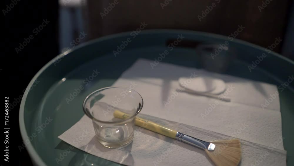 Massage therapist squeezes cream into a glass as she prepares for her facial massage. Steadicam shot. Massage therapist squeezes cream into a glass as she prepares for her facial massage. Steadicam shot.