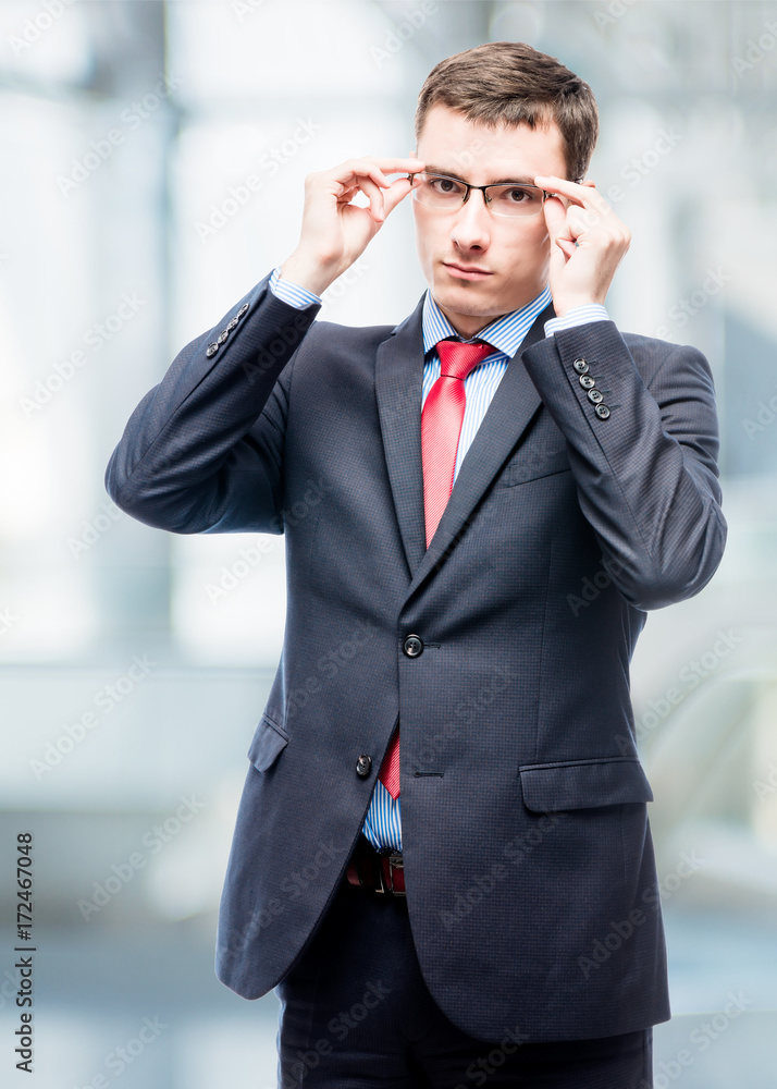 Serious businessman corrects glasses portrait in office Serious businessman corrects glasses portrait in office