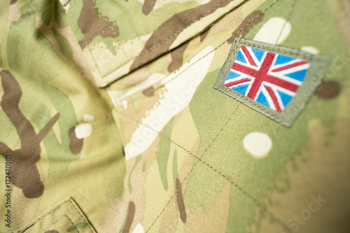 Union Jack / union flag badge on a British army camouflage uniform. Text / writing / copy space surrounding badge.