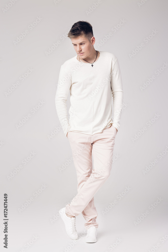 handsome young man in a white sweater and pants handsome young man in a white sweater and pants