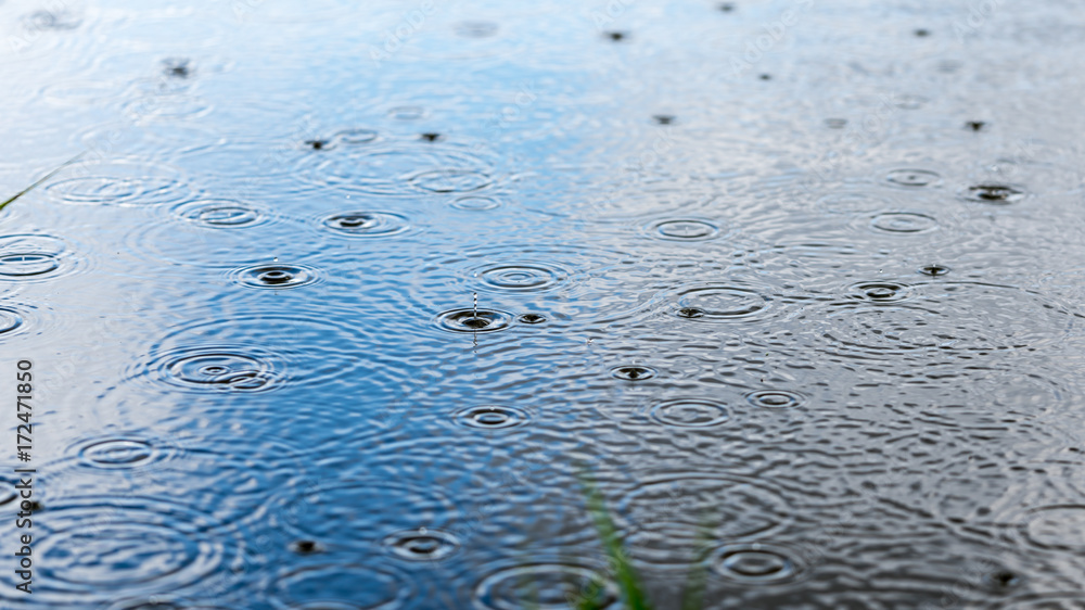 tranquill and calm raindrops falling on reflective water making beautiful interference patterns