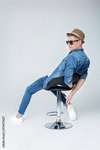 handsome man in denim sits on chair 
