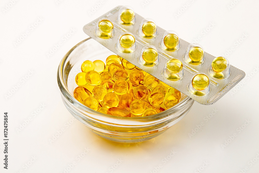 Сapsules with vitamins A and E. Yellow capsuls in glass bowl and blister with capsules. Copy space Сapsules with vitamins A and E. Yellow capsuls in glass bowl and blister with capsules. Copy space
