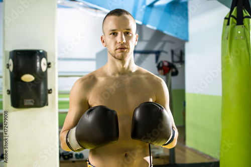 Attractive shirtless young man with boxing gloves in sports hall. © Bojan