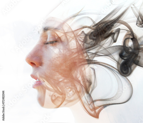 Double exposure portrait of a young fair-skinned woman and a smoky texture dissolving into her facial features photo
