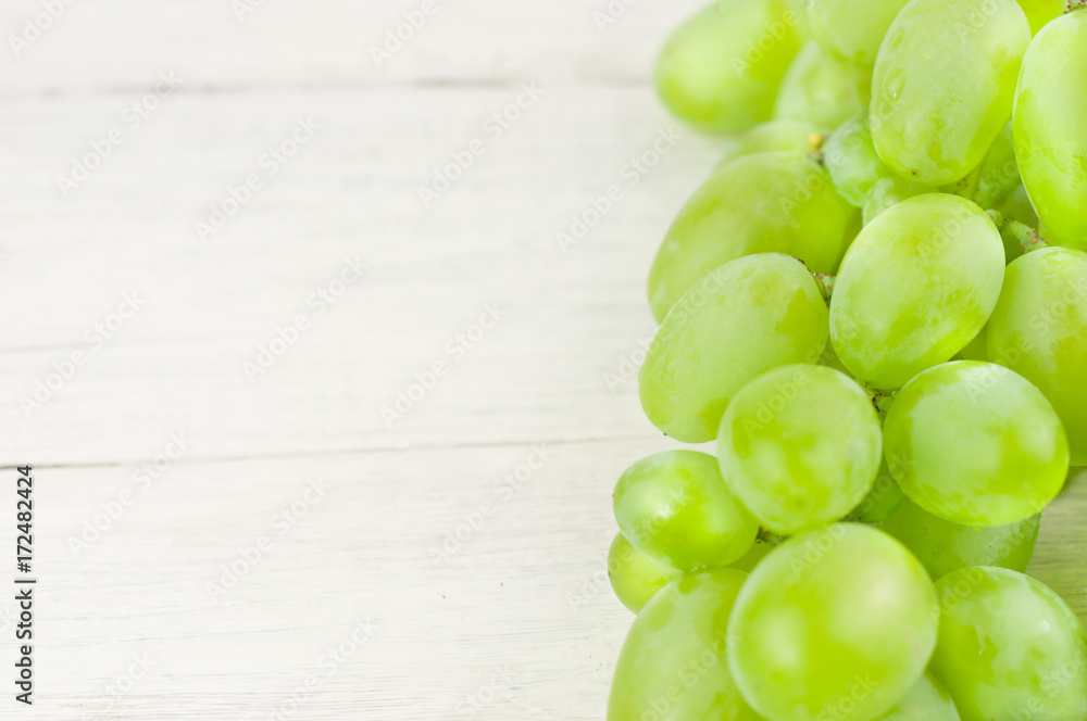 Bunch of fresh ripe green grapes on old wooden rustic white planks Bunch of fresh ripe green grapes on old wooden rustic white planks