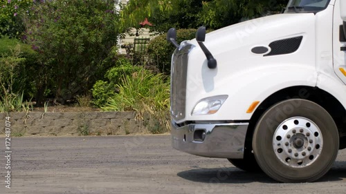 Close view of white truck and trailer pulling away from parking space on summer day in rural area. Side view, real-time 4K.