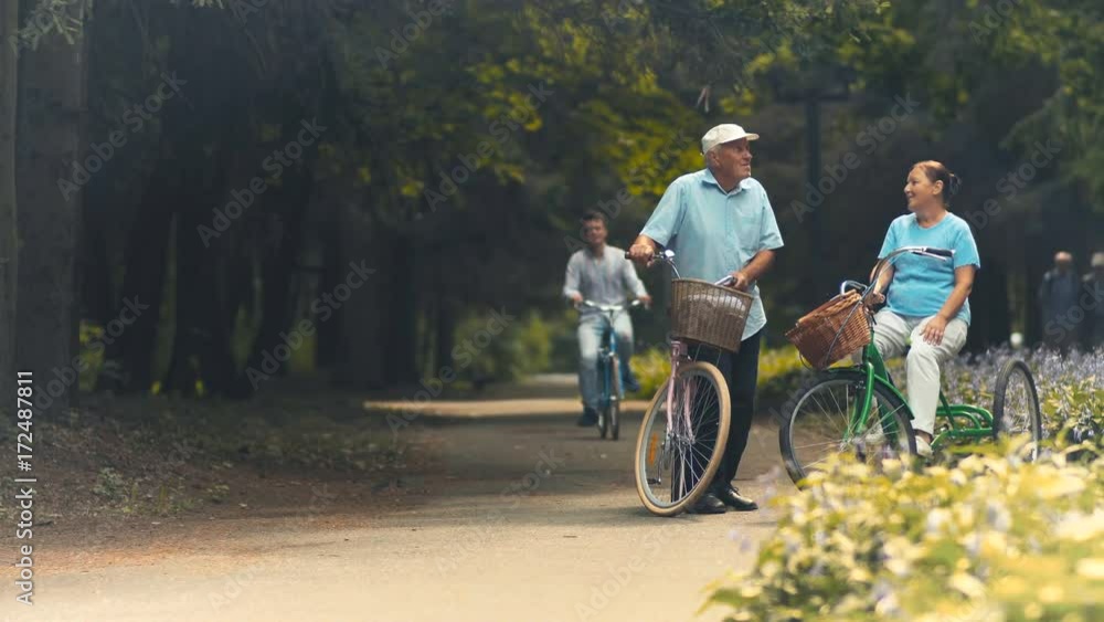 Young guy invites old couple on bicycles to ride with him in park Young guy invites old couple on bicycles to ride with him in park