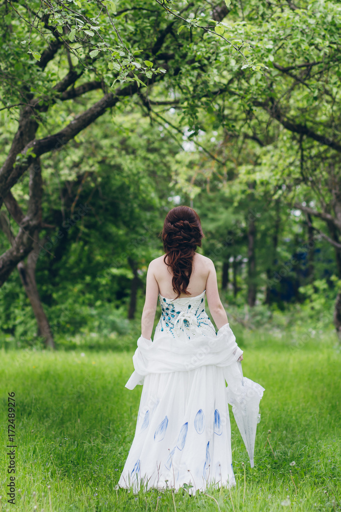 Woman in long white dress in summer garden Woman in long white dress in summer garden