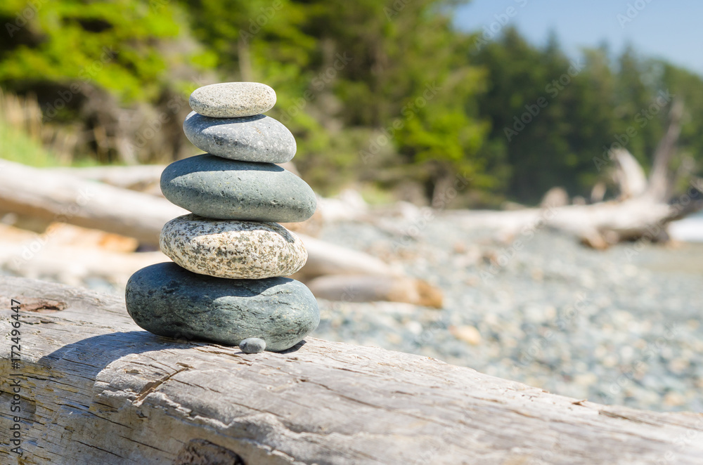 Stack of Balanced Stones on Driftwood on a Beach on a Sunny Spring Day. Concept of Meditation and Harmony. Stack of Balanced Stones on Driftwood on a Beach on a Sunny Spring Day. Concept of Meditation and Harmony.