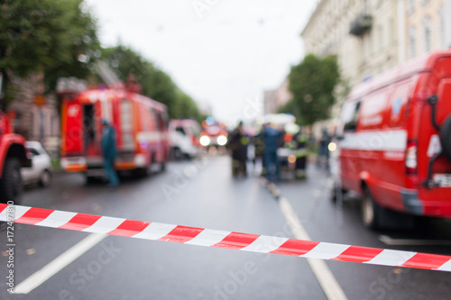 Red and White Lines of barrier tape on the background of firefighters and fire trucks at work.. Red White warning tape pole fencing is protects for No entry © Vasiliy