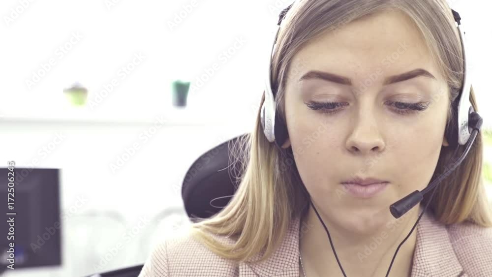 The operator of the hotline with headsets, sit at the computer in the office and advise clients. Workers call-center, a woman talking to customers. She prints on the computer and answers questions. The operator of the hotline with headsets, sit at the computer in the office and advise clients. Workers call-center, a woman talking to customers. She prints on the computer and answers questions.