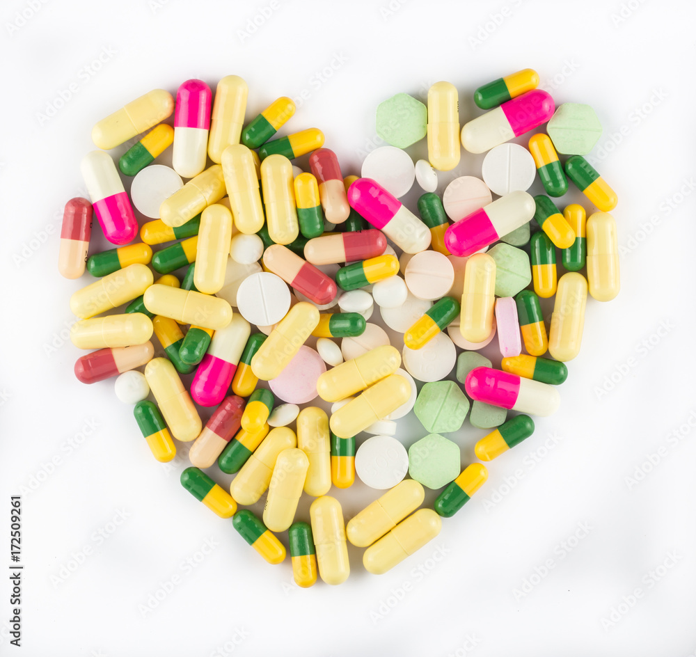 Colorful drug pills in shape of heart on white background, pharmaceutical concept Colorful drug pills in shape of heart on white background, pharmaceutical concept