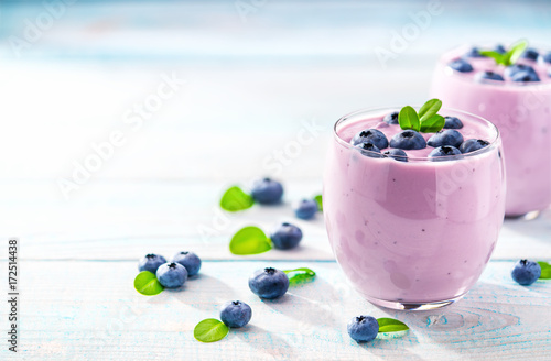 Two glasses of blueberry smoothie on a turquoise wooden backgrou