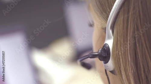 The operator of the hotline with headsets, sit at the computer in the office and advise clients. Workers call-center, a woman talking to customers. She prints on the computer and answers questions.