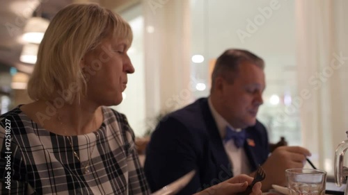 Business meals. Woman having dinner while her husband using tablet PC and talking to business partner photo