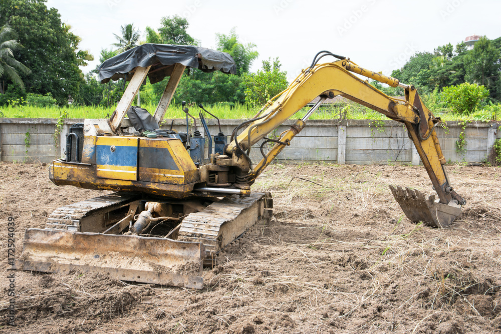 Old Yellow excavator parked.Old small excavator parked outdoor.Excavator parking off field Old Yellow excavator parked.Old small excavator parked outdoor.Excavator parking off field