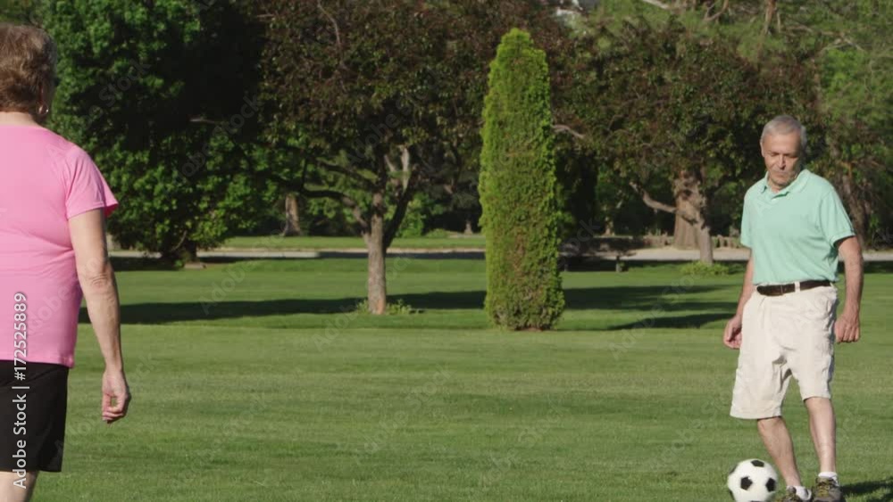 Elderly couple playing with soccer ball in park Elderly couple playing with soccer ball in park