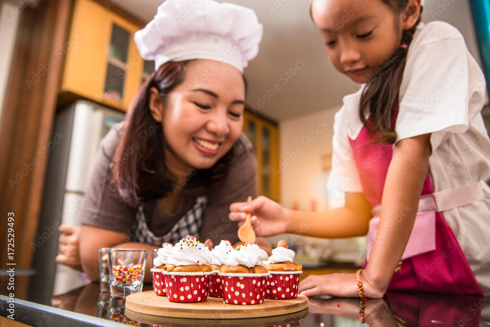 Asian mother and daughter enjoy making and decorate bakery cake in real life kitchen, Concept of family cooking Asian mother and daughter enjoy making and decorate bakery cake in real life kitchen, Concept of family cooking