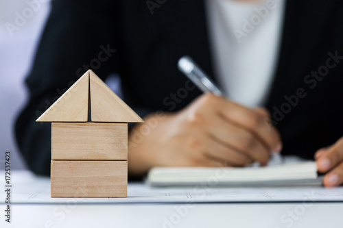 Fotografie Close-up of house architectural model with businessperson signs contract behind blur background