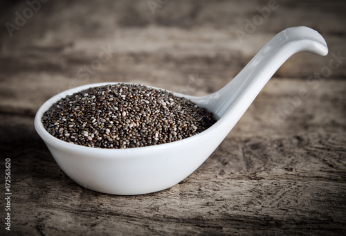 Healthy Chia seeds in spoon on wooden background.