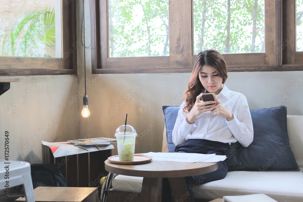 Front view of attractive young Asian woman looking mobile smart phone in coffee shop. Front view of attractive young Asian woman looking mobile smart phone in coffee shop.
