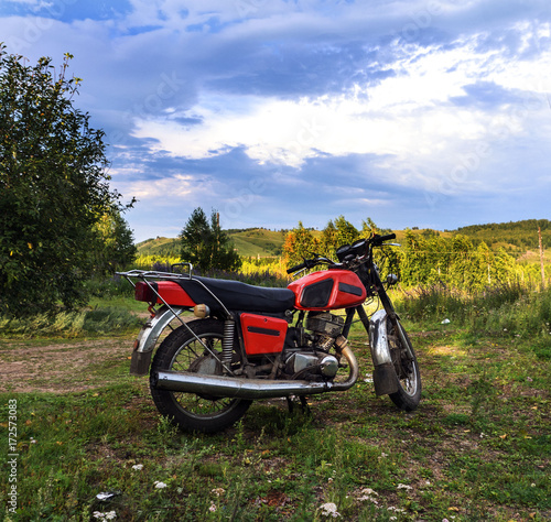 Motorcycle suitcases standing on a forest road. Sky and mountains view.