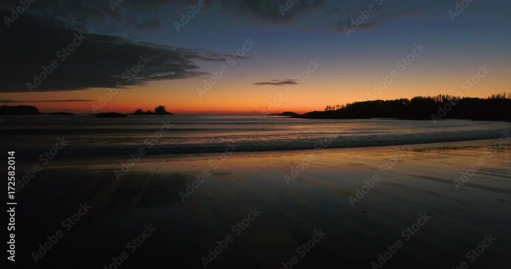 Slow aerial shot flying over a beach during an orage sunset Slow aerial shot flying over a beach during an orage sunset