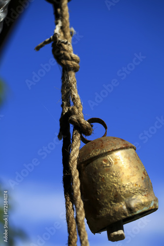 old bell hanging on a rope against a blue sky background