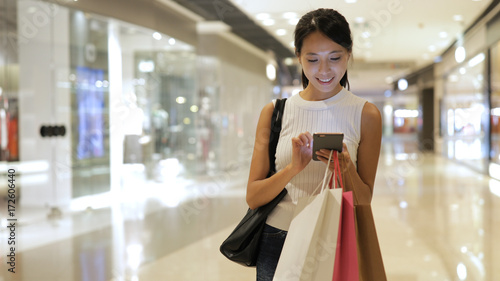 Fotografie Shopping woman using smart phone at shopping center