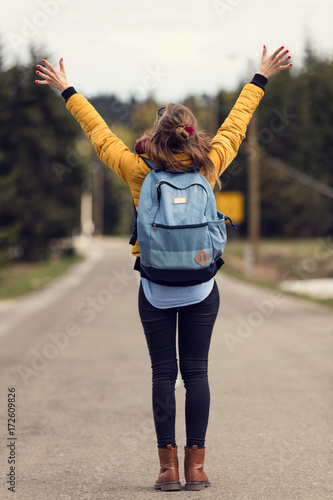 Girl walking down the empty road with arms wide open.