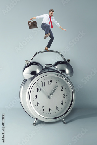 Fotografie Businessman balancing over alarm clock.