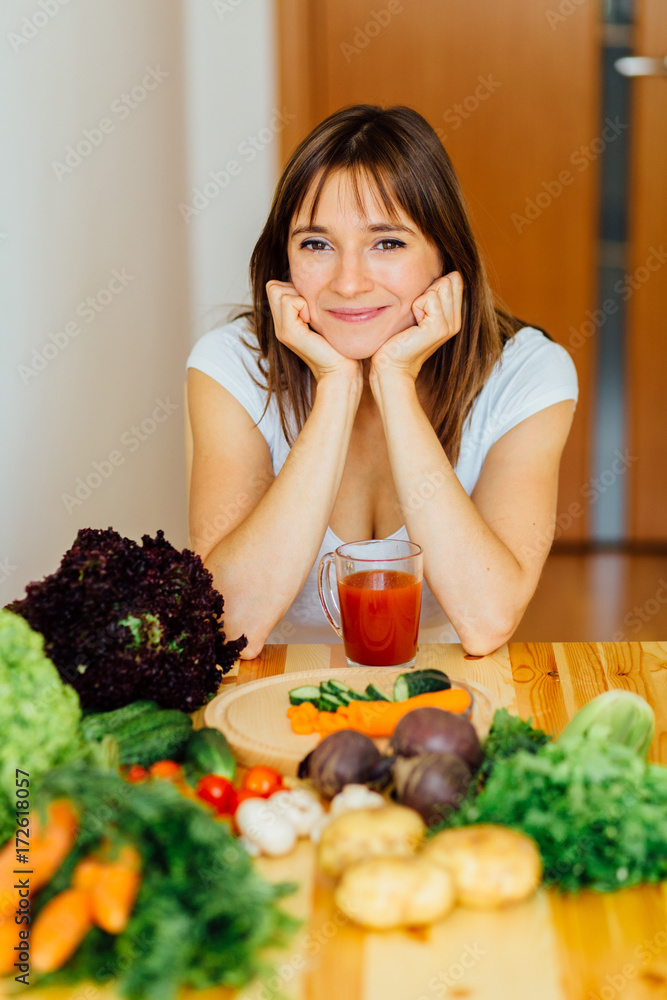 The young happy brunette woman with the fresh vegetables on the home kitchen. Healthy eating, cooking, food, dieting and people concept. The young happy brunette woman with the fresh vegetables on the home kitchen. Healthy eating, cooking, food, dieting and people concept.